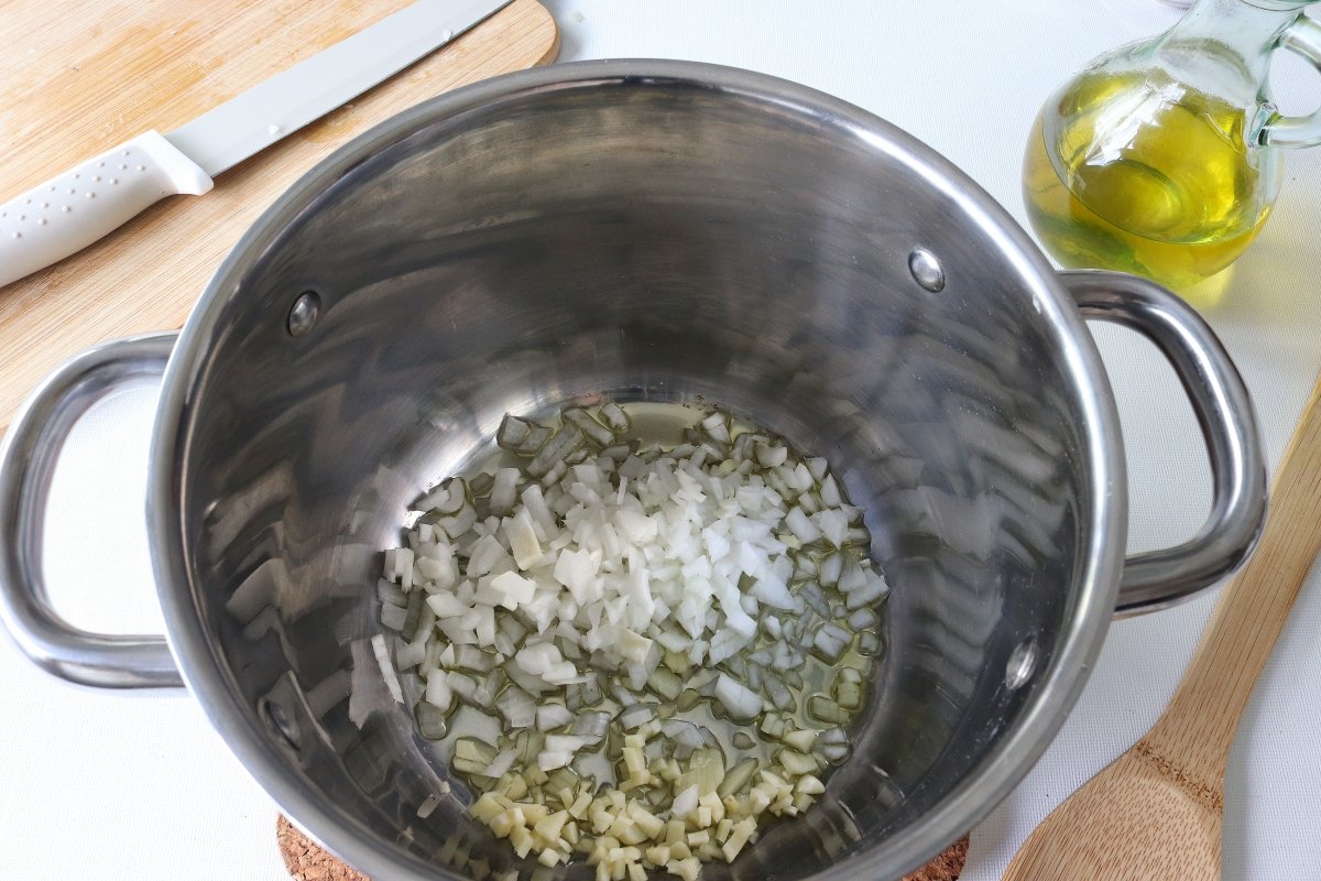 Pochar cebolla y ajos para hacer la sopa de coliflor con setas
