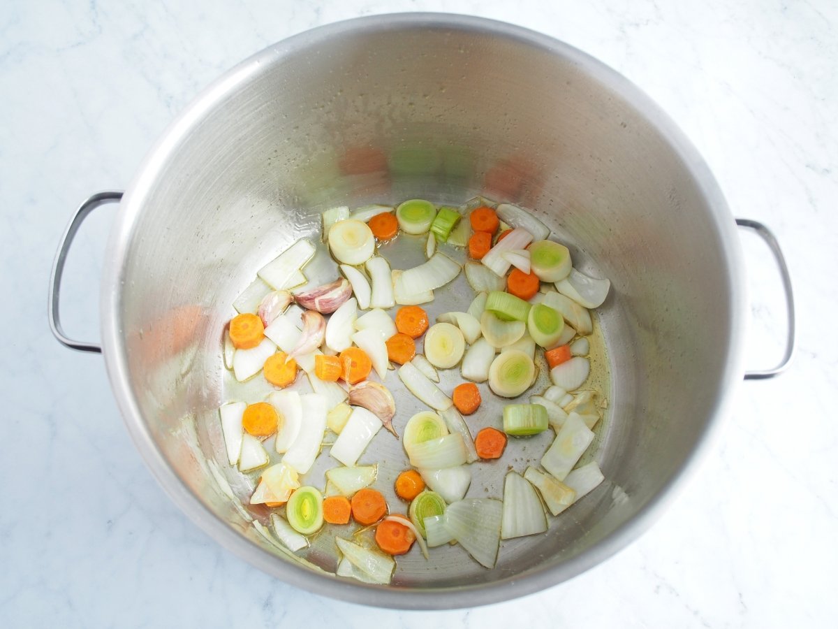 Pochar las verduras en la olla para hacer la sopa de marisco