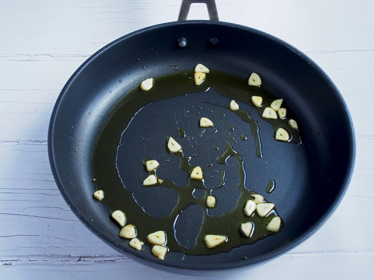 Ponemos una sartén a fuego medio con aceite de oliva, cocinamos los ajos 2 minutos y los retiramos