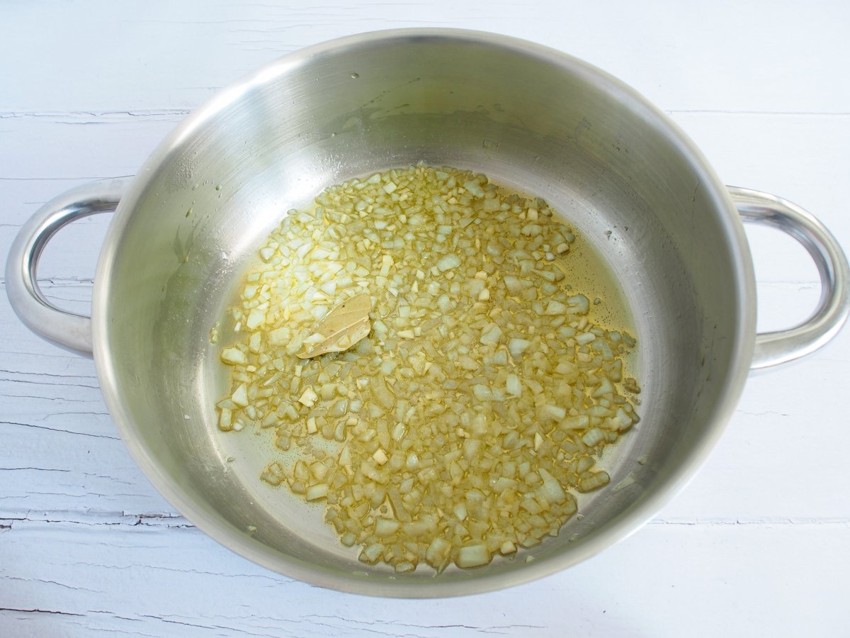 Ponemos una tartera con aceite de oliva a fuego medio y sofreímos el ajo. Añadimos la cebolla, una h