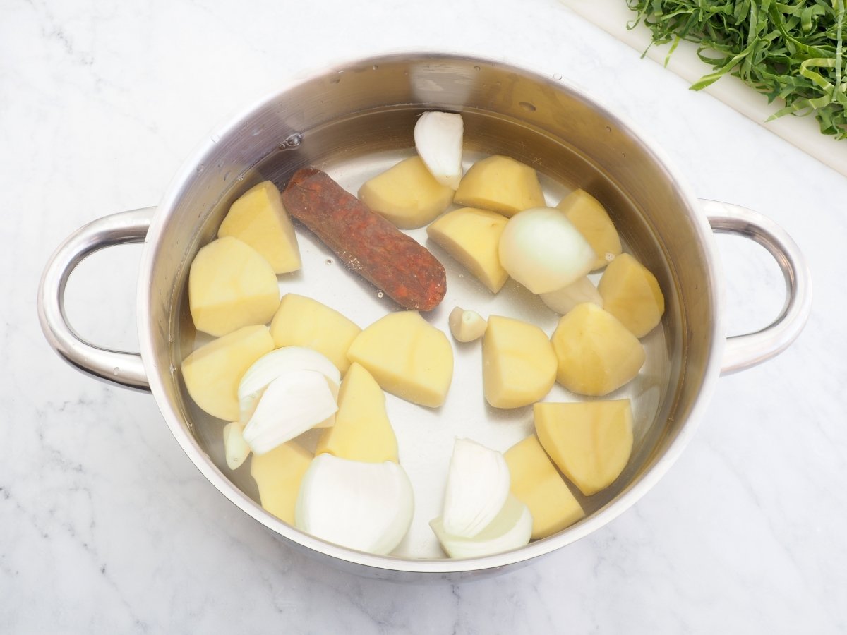 Poner a cocer el chorizo con las patatas y la cebolla