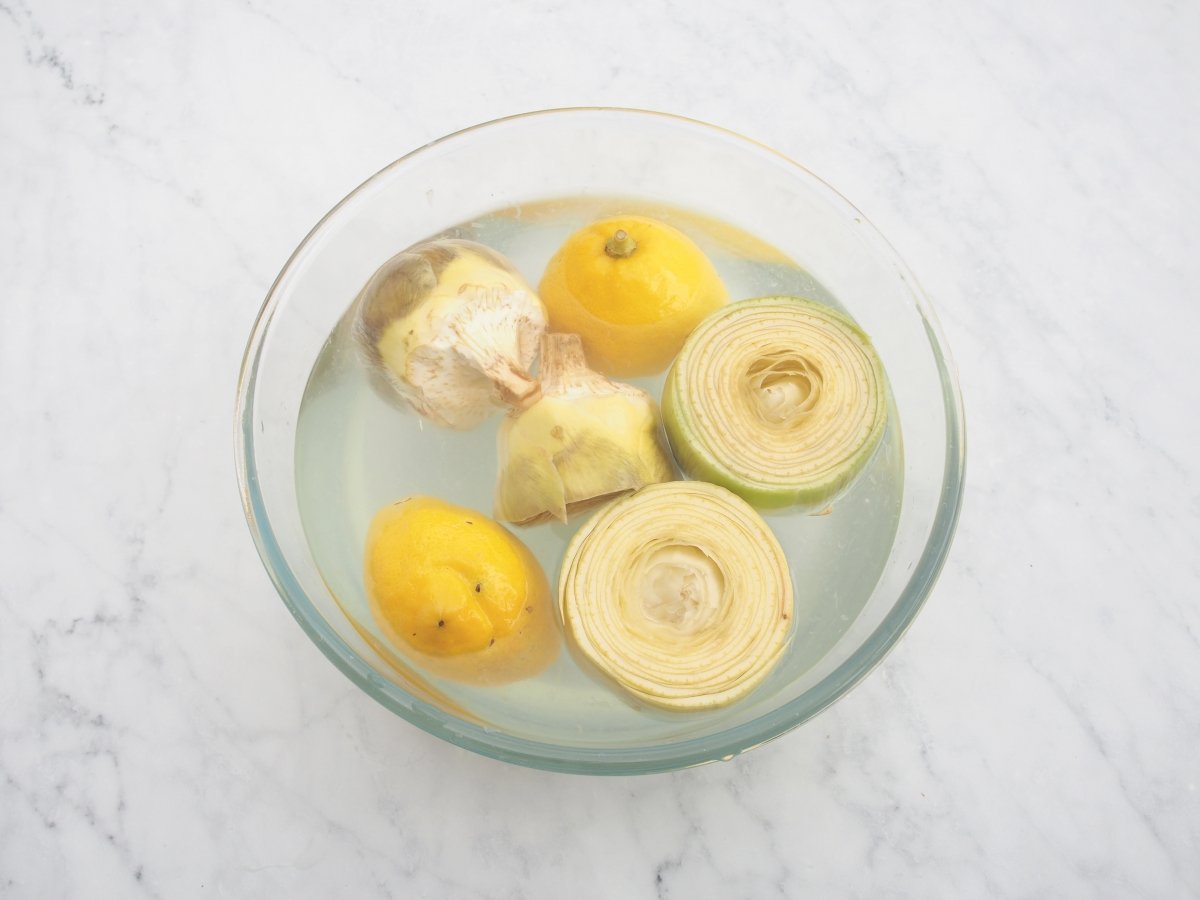 Poner las alcachofas en agua con limón para la crema de alcachofas