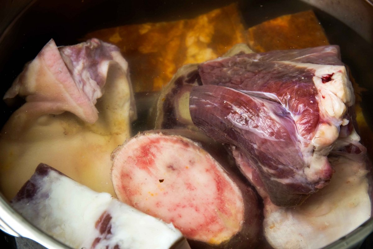 Poner las carnes en la olla para hacer el cocido lebaniego