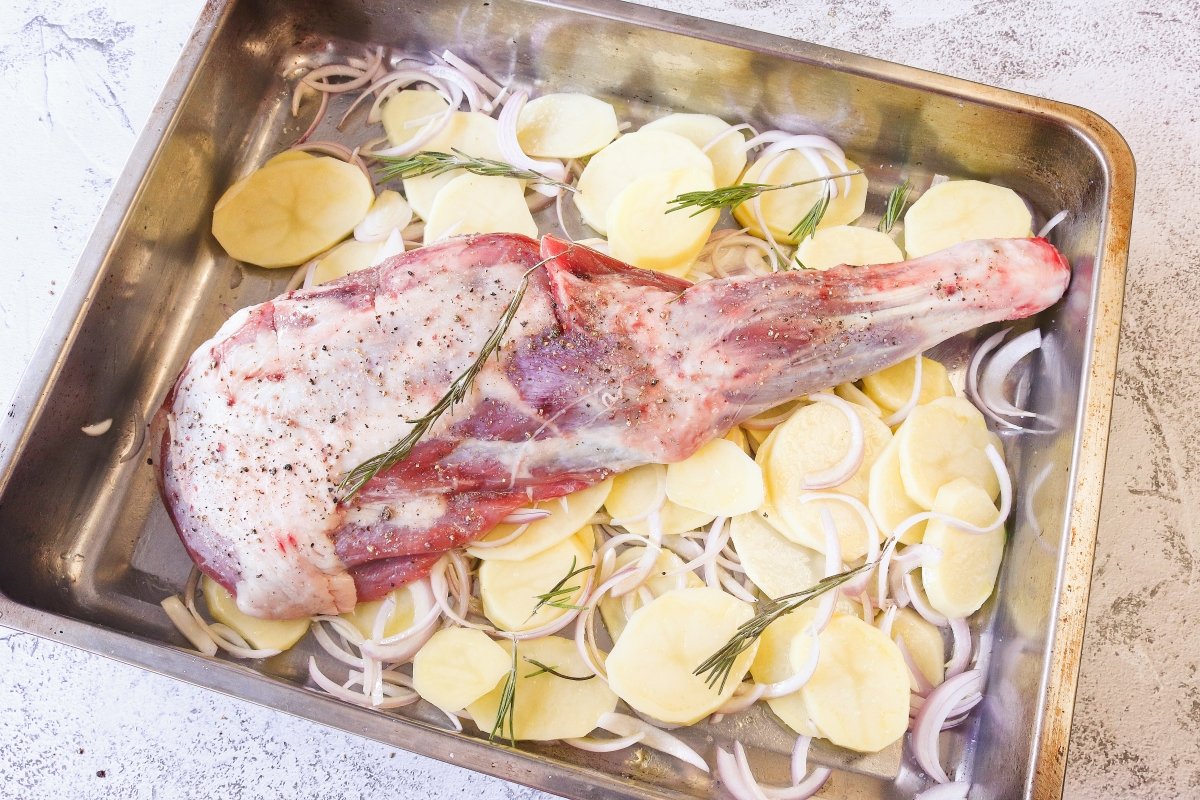 Poner las patatas y la paletilla de cordero en la bandeja de horno