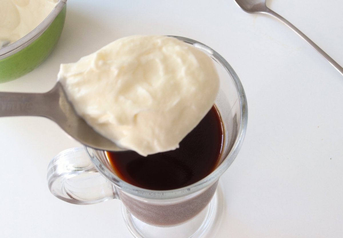 Putting an Irish coffee cocktail with whipped cream
