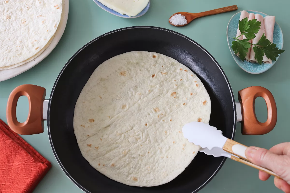 Poner tortilla en sartén sincronizadas de jamón y queso