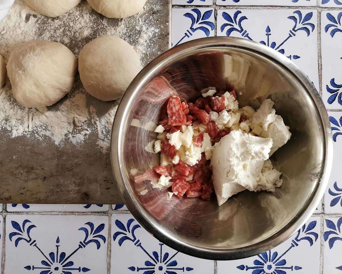 Preparar el relleno: en un bol mezclar la ricotta, la mozzarella cortada en daditos y el salchichón