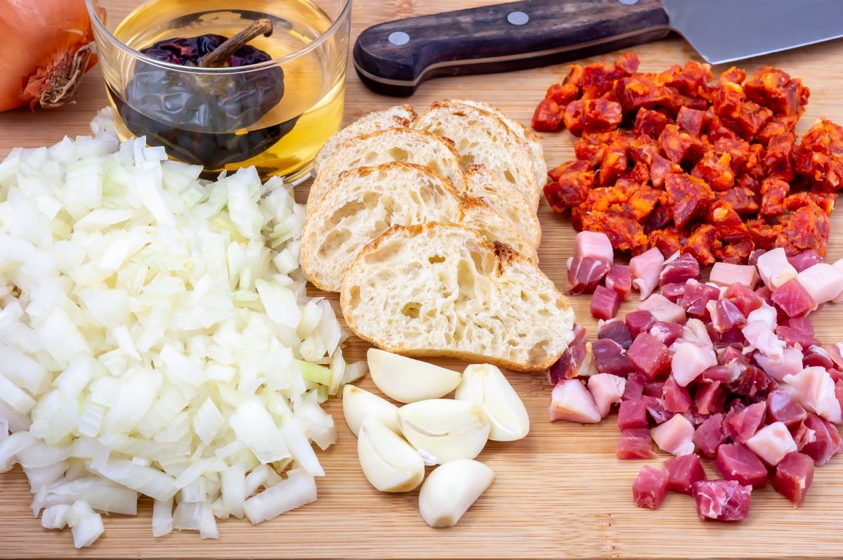 Preparar la cebolla, los ajos, el jamón y el chorizo para la salsa de los caracoles