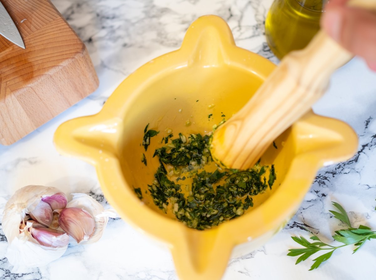 Prepare a picada in the mortar of garlic, parsley and oil for the grilled pig's ear