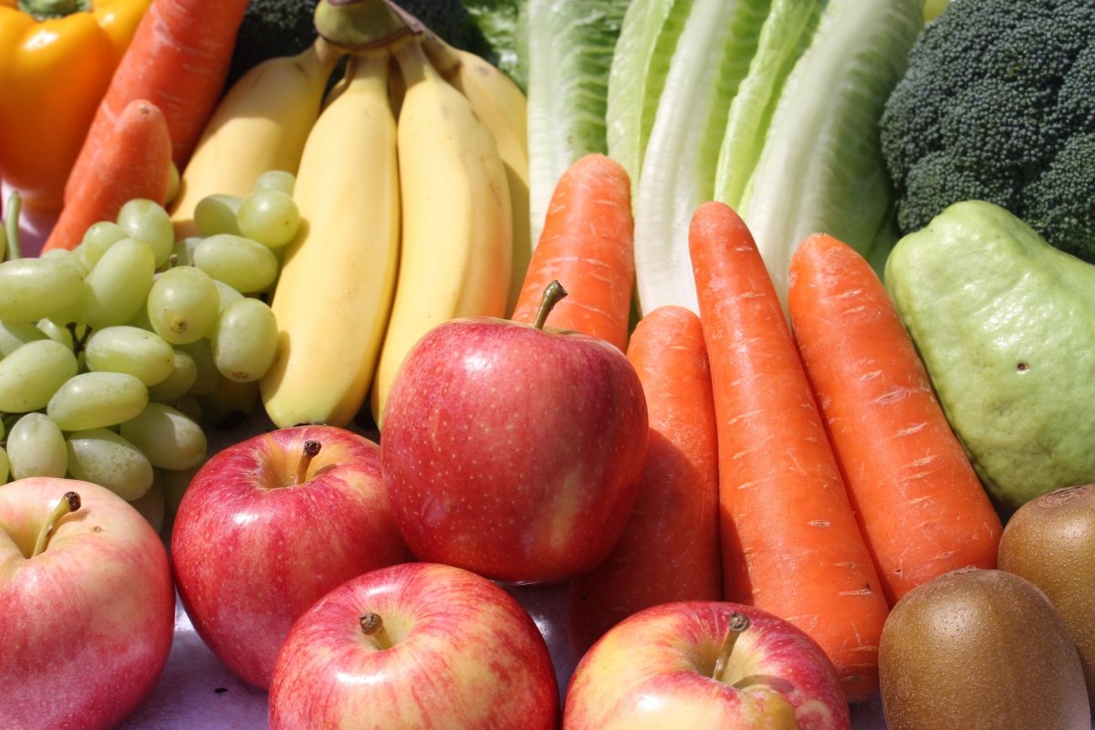 Primer plano de una selección de frutas y verduras como plátanos, zanahorias, uvas, manzanas...