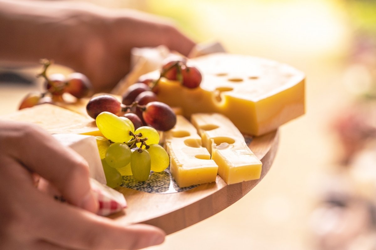 Queso Emmental con uvas blancas y rojas en tabla de quesos