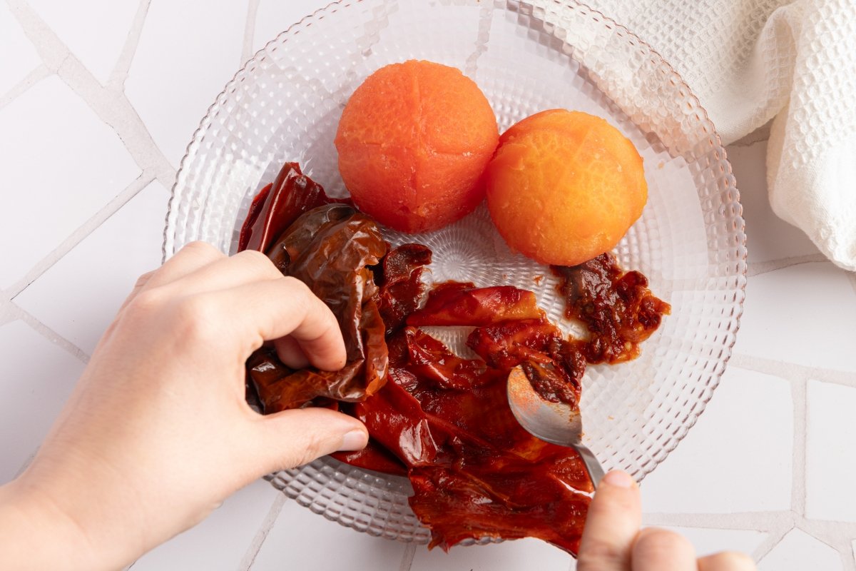 Quitando la carne a los pimientos secos para el ajo colorao