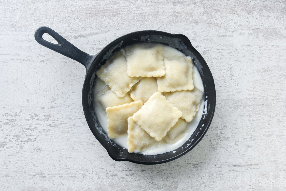 Raviolis escurridos sobre salsa de queso
