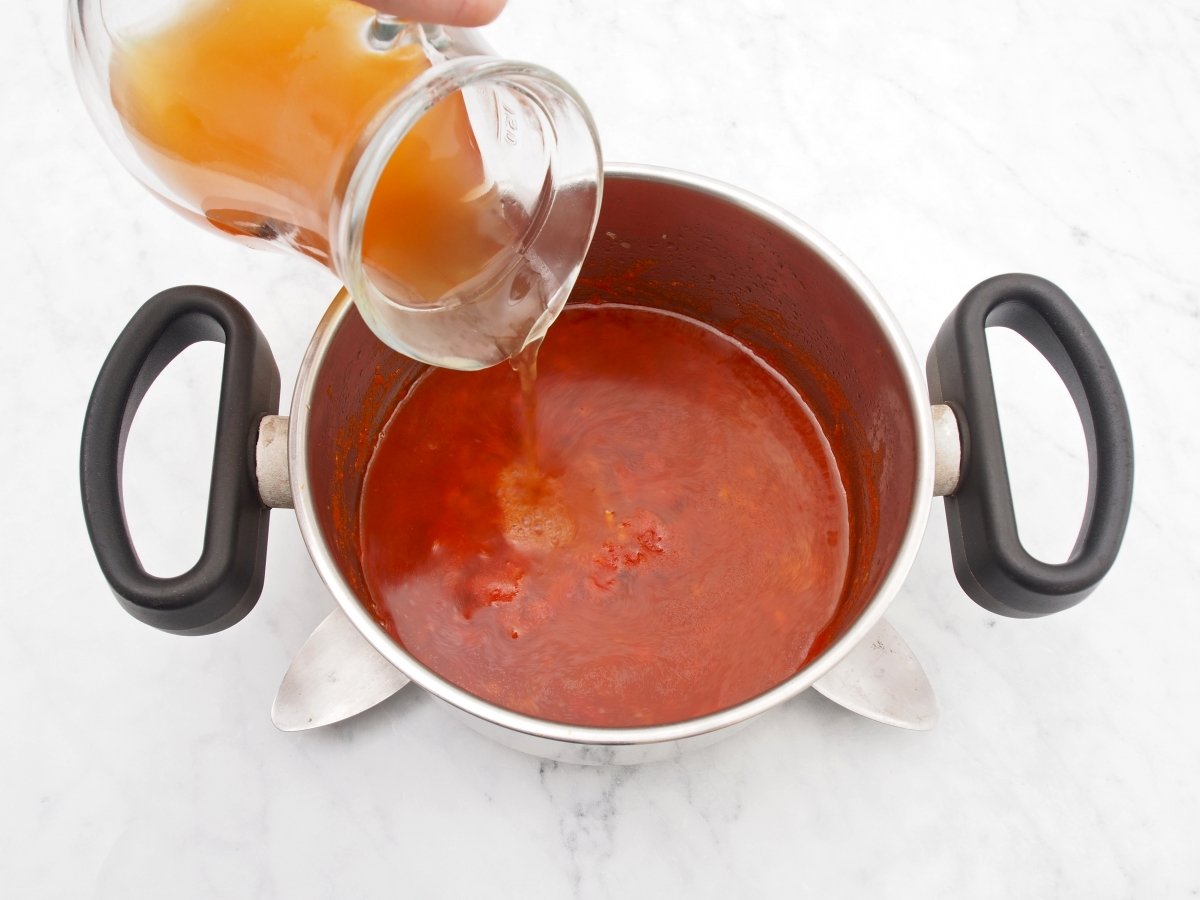 Regar cazuela con caldo para hacer la salsa brava