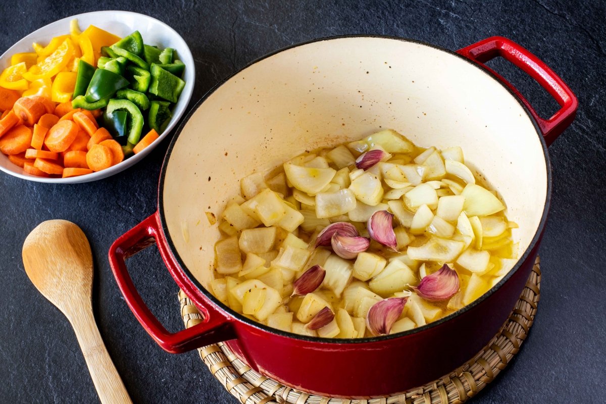 Rehogar la cebolla y los ajos para el estofado de pollo con patatas y verduras