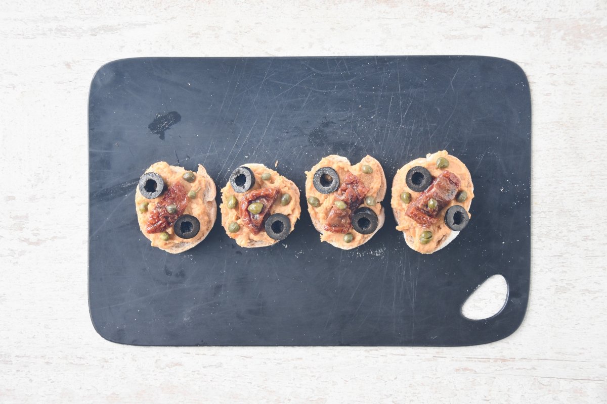 Repartimos las olivas, las alcaparras y el tomate en aceite