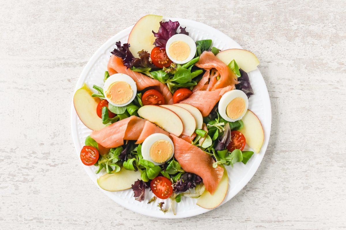 Repartimos los ingredientes de la ensalada de salmón ahumado en un plato