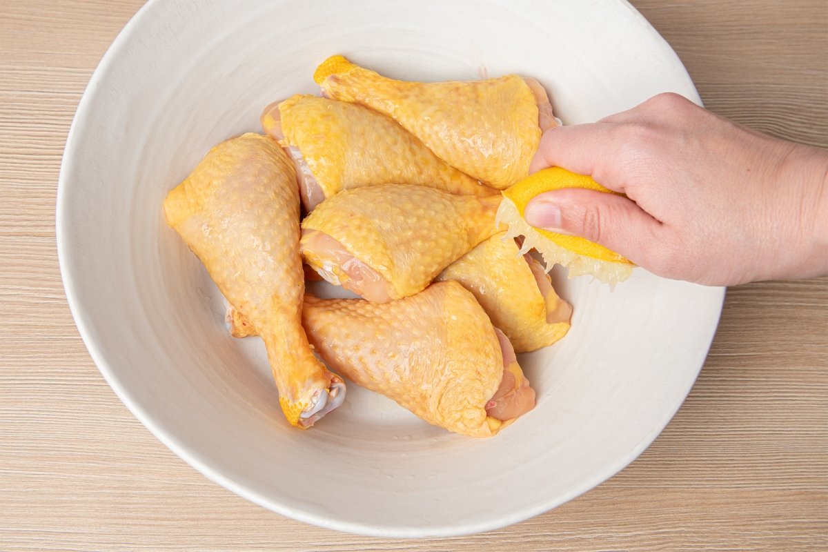 Rociando limón sobre el pollo para los muslos de pollo en freidora de aire