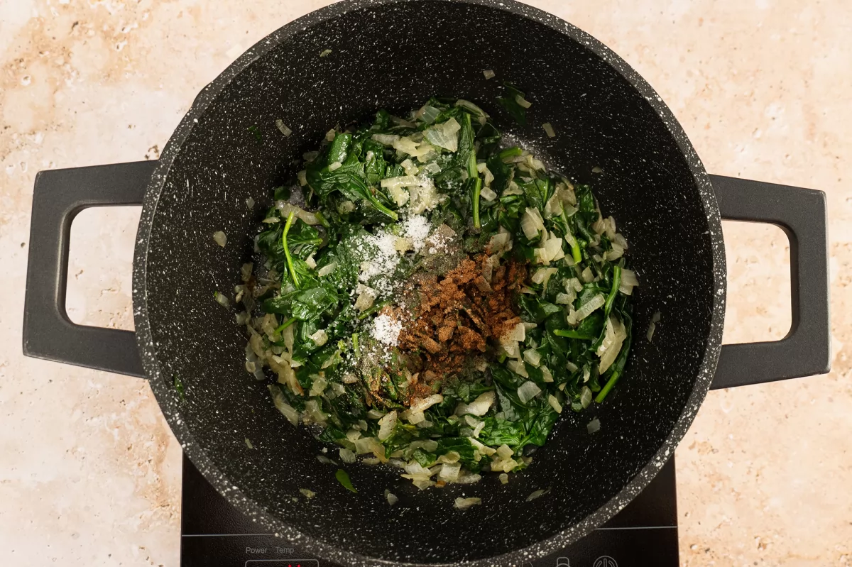 Salpimentar el sofrito de espinacas para la torta pascualina
