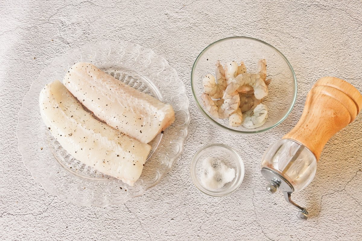 Salpimentar la merluza y las gambas para hacerlas con salsa de cava