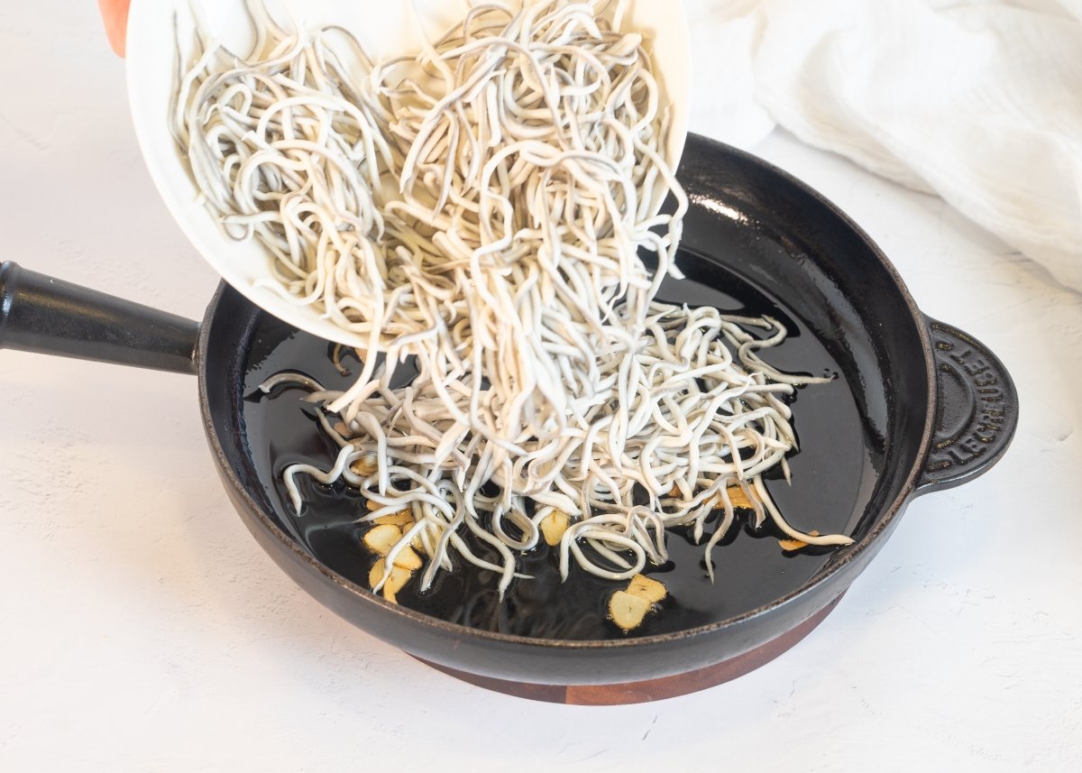 Salteando las gulas con ajo para hacer huevos rotos con gulas