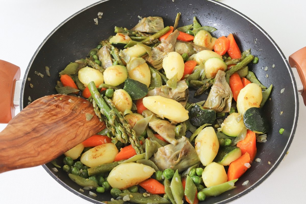 Saltear las verduras cocidas con los guisantes para el panaché de verduras