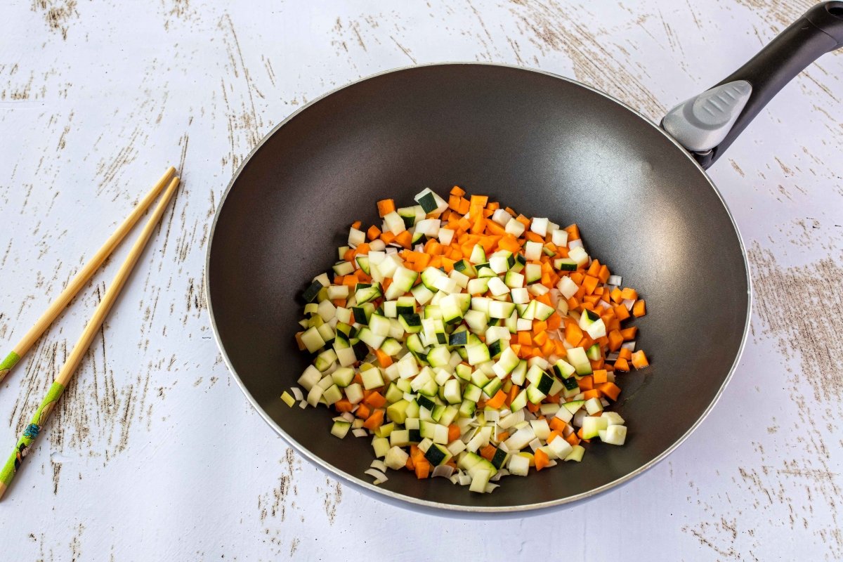 Saltear las verduras en el wok para hacer el yakimeshi o arroz frito japonés
