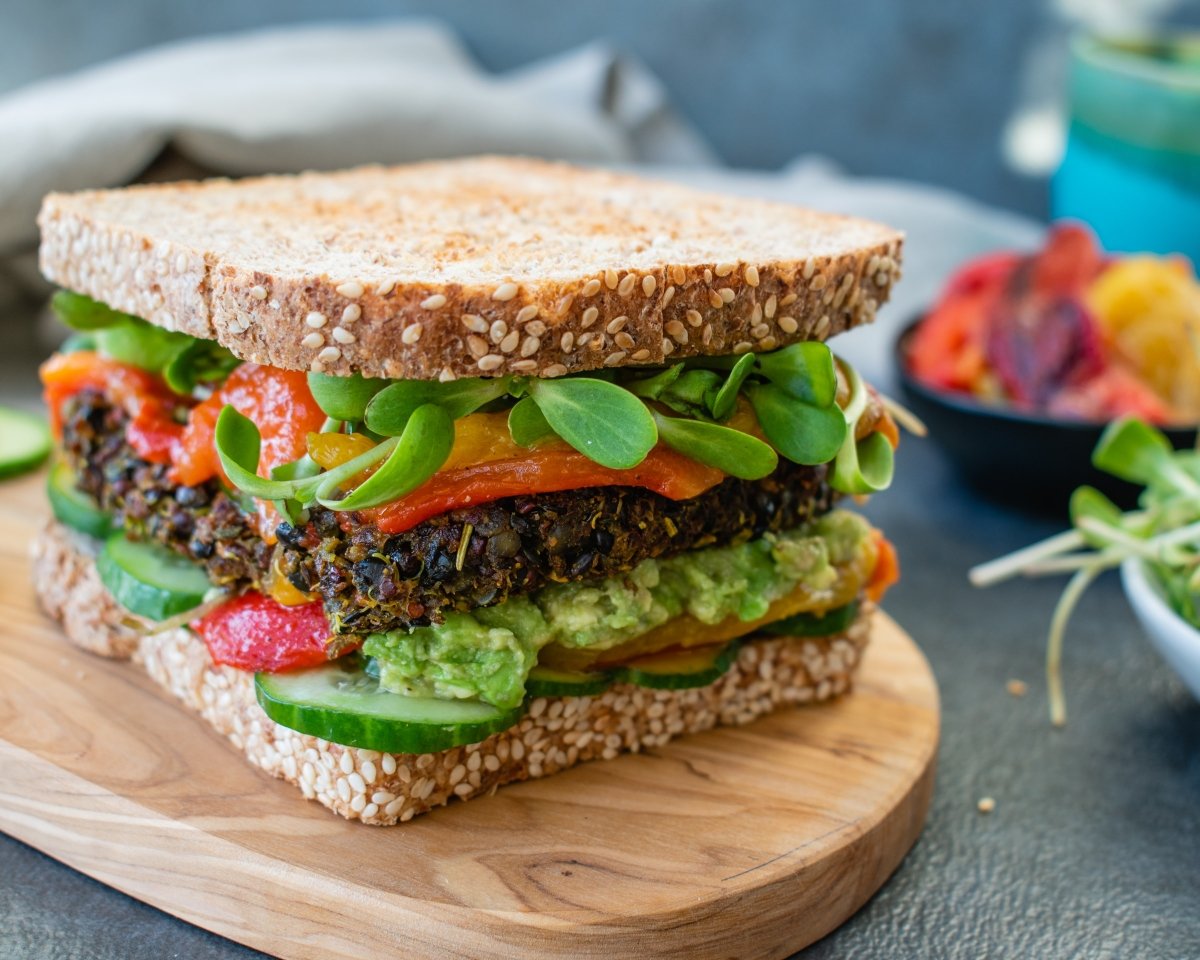 Sándwich con carne vegana, tomate, aguacate y canónigos