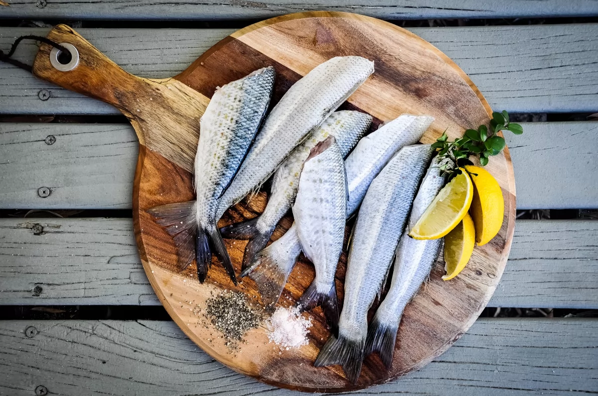 Sardinas frescas con limón sobre una tabla de cortar de madera