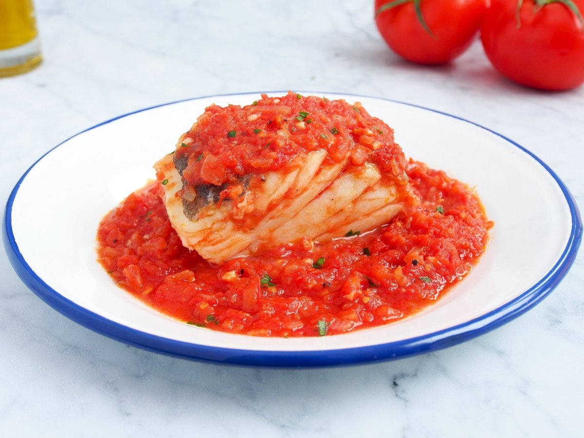 Servir el bacalao con tomate con perejil picado por encima
