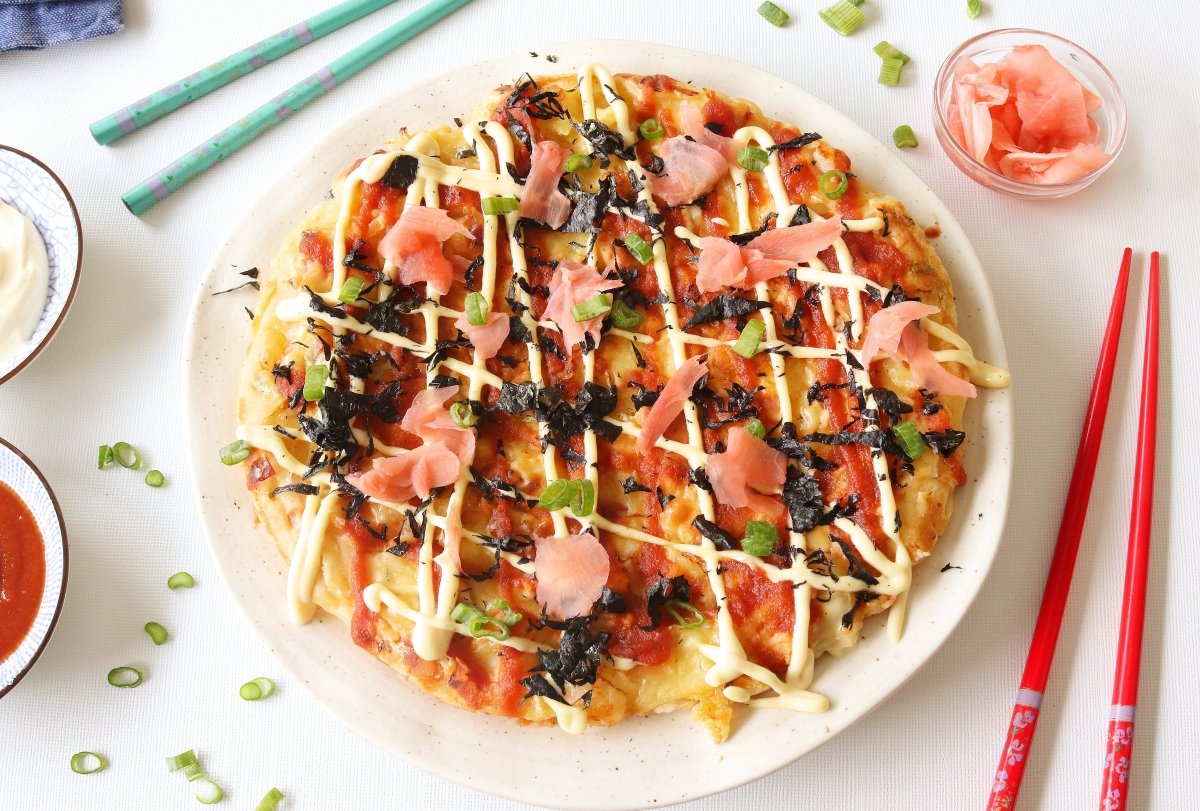 Servir el okonomiyaki con la mayonesa, la salsa, copos de bonitos y alga nori