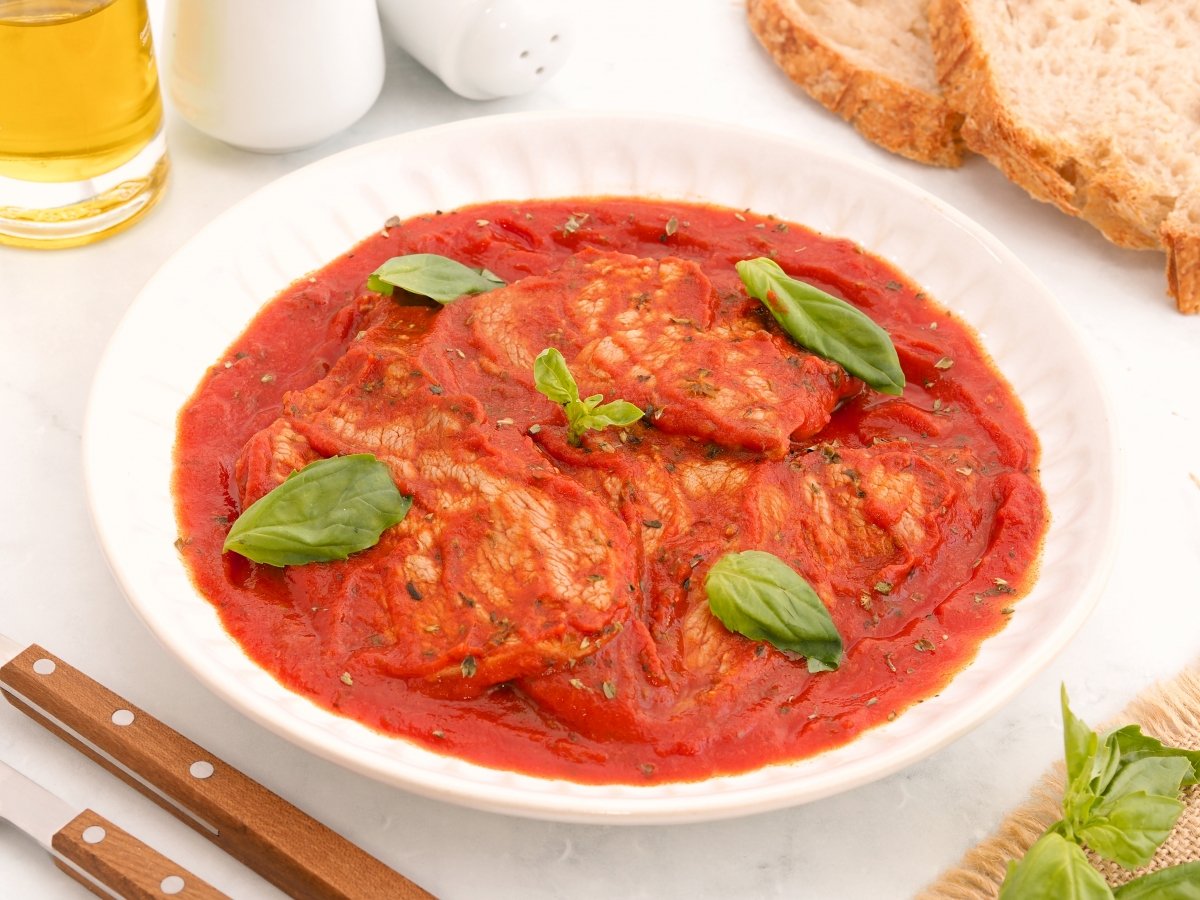 Servir la carne a la pizzaiola con albahaca fresca