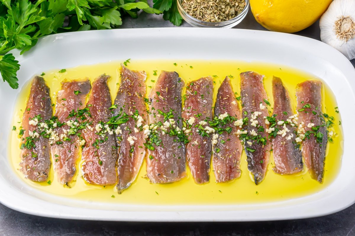 Servir las sardinas marinadas con ajo, perejil, aceite y limón
