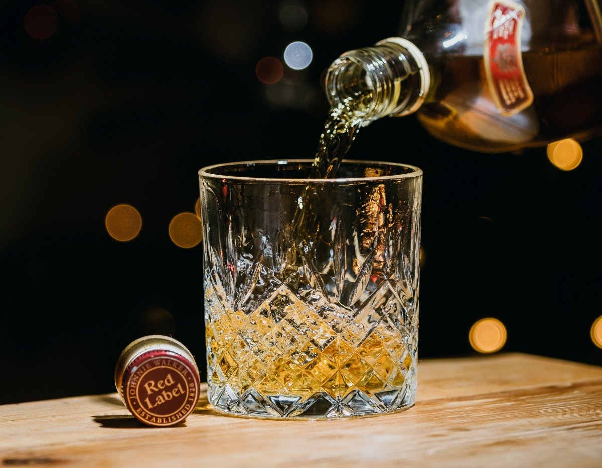 Sirviendo whisky de la botella a un vaso de cristal