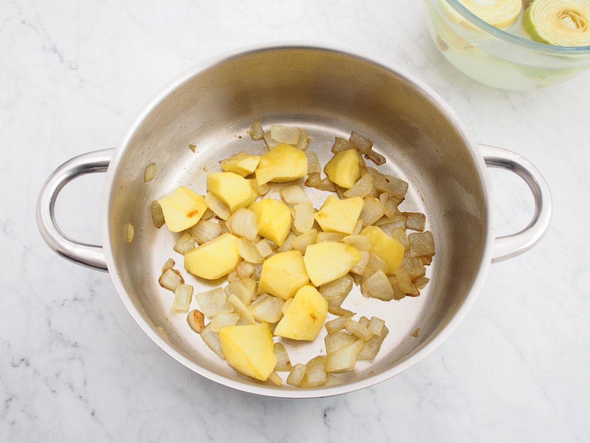 Sofreír la cebolla con la patata para la crema de alcachofas