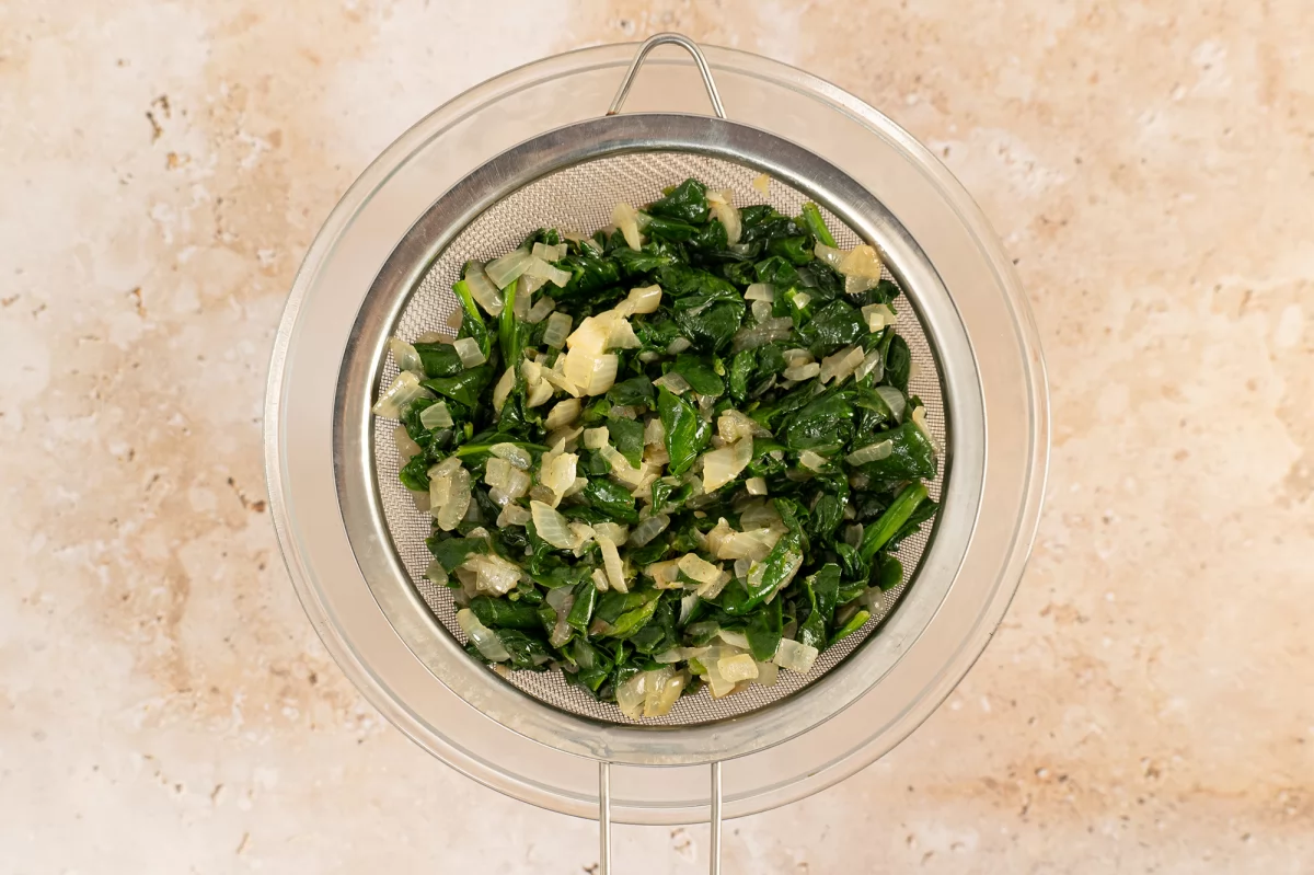 Sofrito de espinacas en un colador para la torta pascualina
