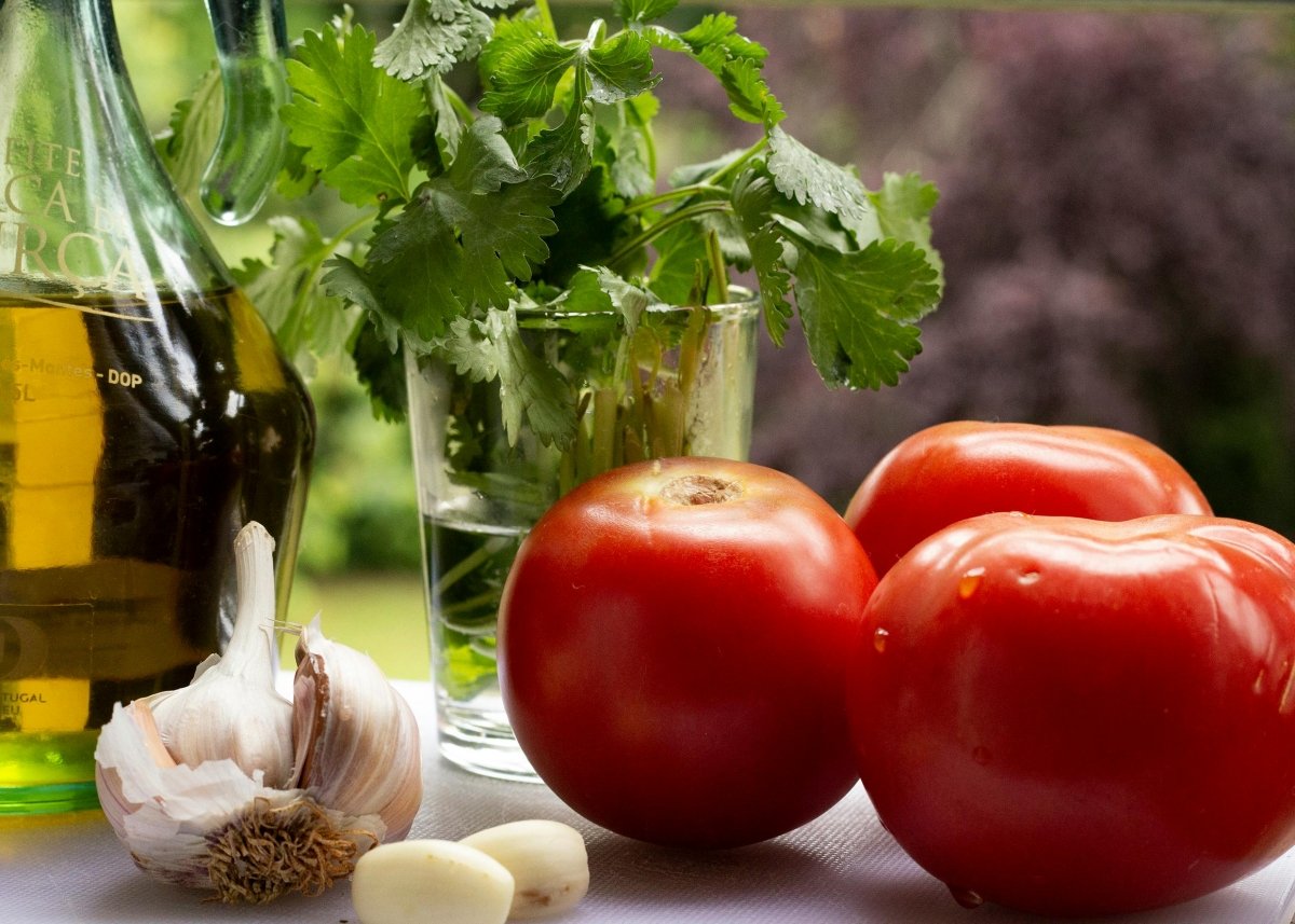 Tomates frescos listos para confitar con aceite de oliva, ajo y perejil