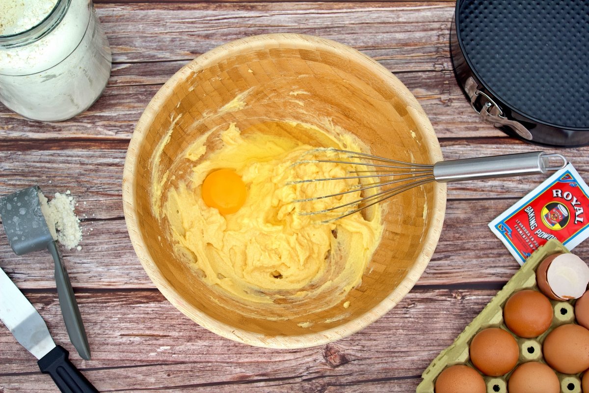 Un huevo añadido al bol con el azúcar y la mantequilla del bizcocho de dulce de leche
