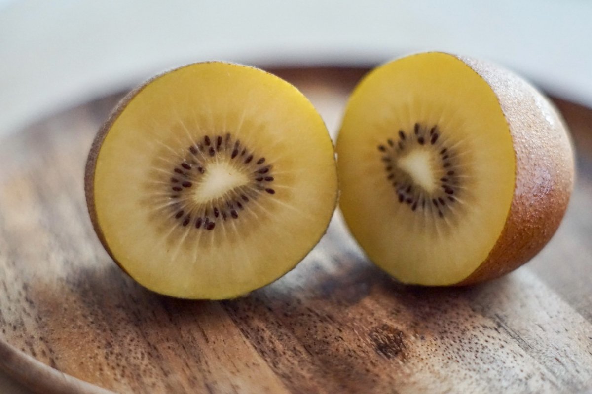 Un kiwi amarillo abierto por la mitad sobre una tabla de madera