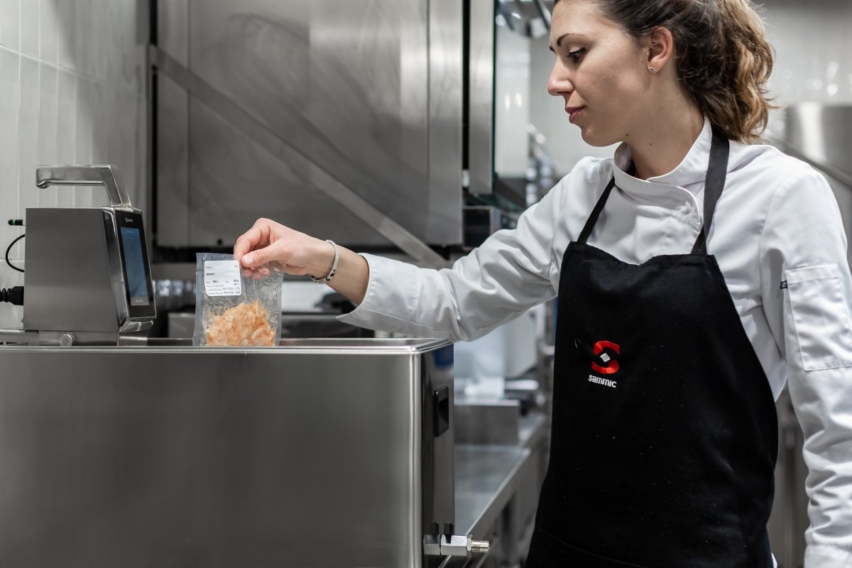 Una cocinera introduce una bolsa en la máquina de cocina sous-vide