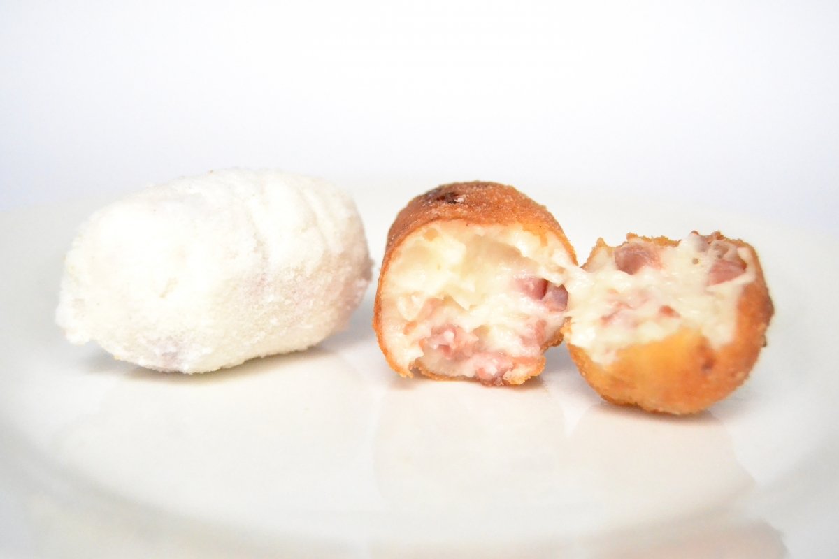 Una croqueta congelada junto a una croqueta frita a la perfección con interior jugoso