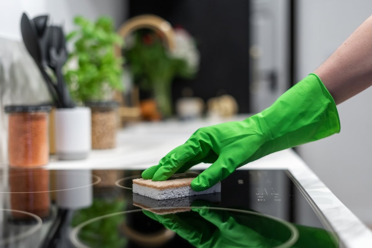 Una persona con guantes limpiando la vitrocerámica