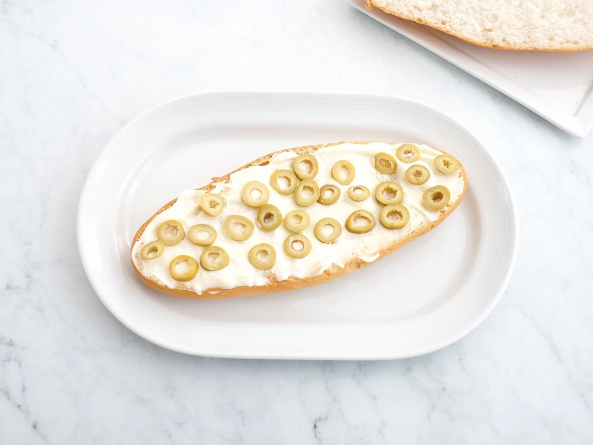 Untar la base del pan con mayonesa y poner aceitunas