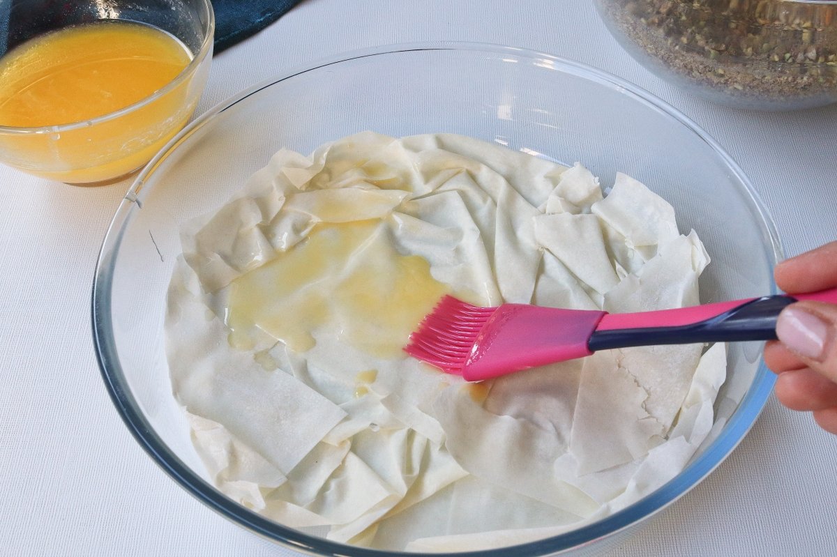 Untar mantequilla a las capas de masa filo para el baklava