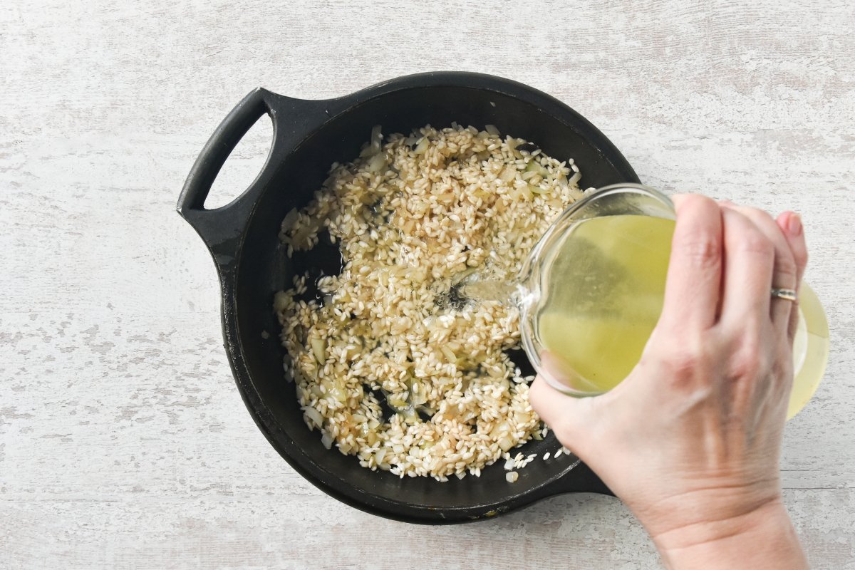 Vertemos caldo para empezar a cocinar el risotto de hongos