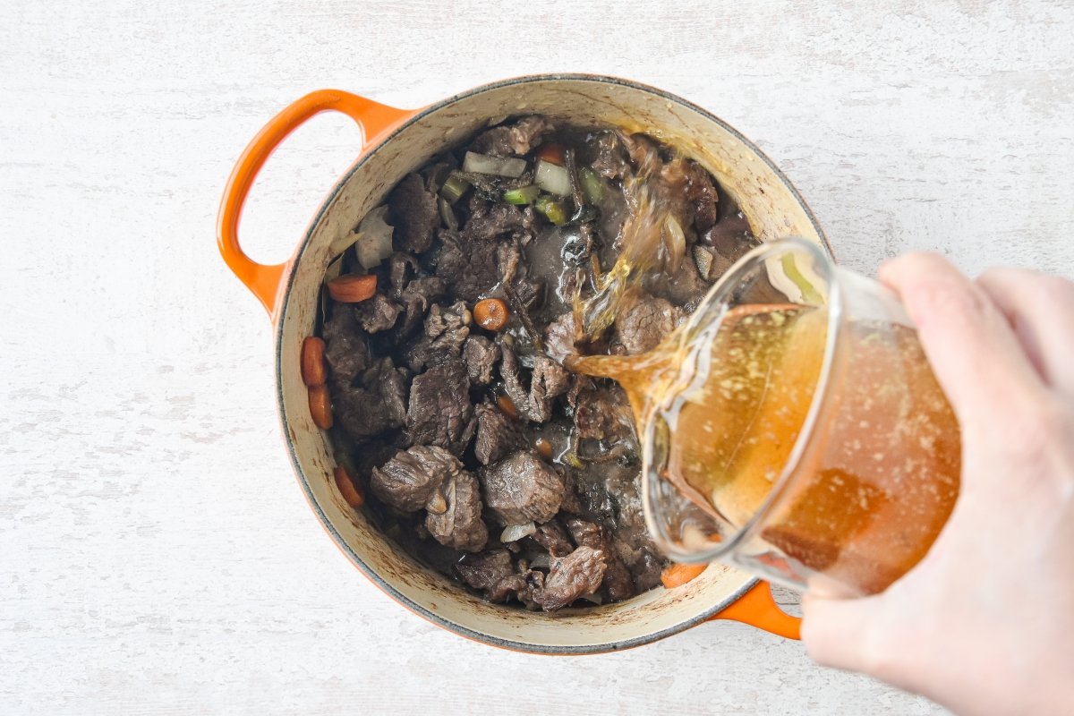 Vertemos el caldo de carne sobre la ternera y las verduras