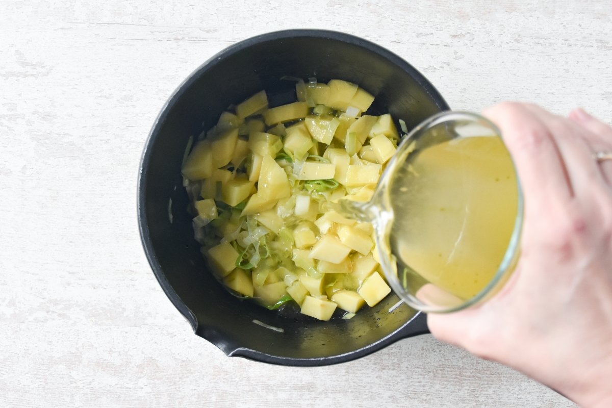 Vertemos el caldo de verduras sobre el puerro y las patatas