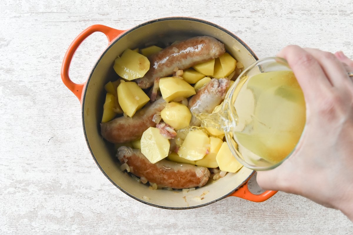 Vertemos el caldo sobre las patatas y las salchichas