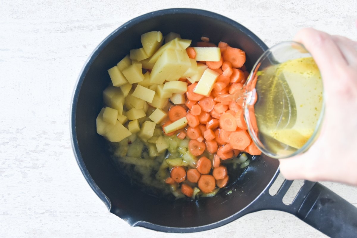 Vertemos el caldo sobre las verduras para la crema de zanahoria