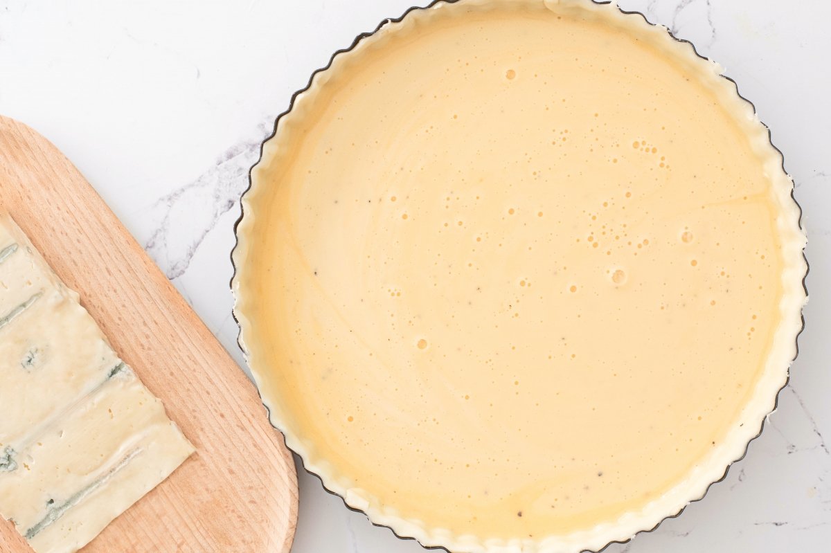 Vertemos el relleno sobre la masa de la tarta salada de queso Gorgonzola y tomates cherry